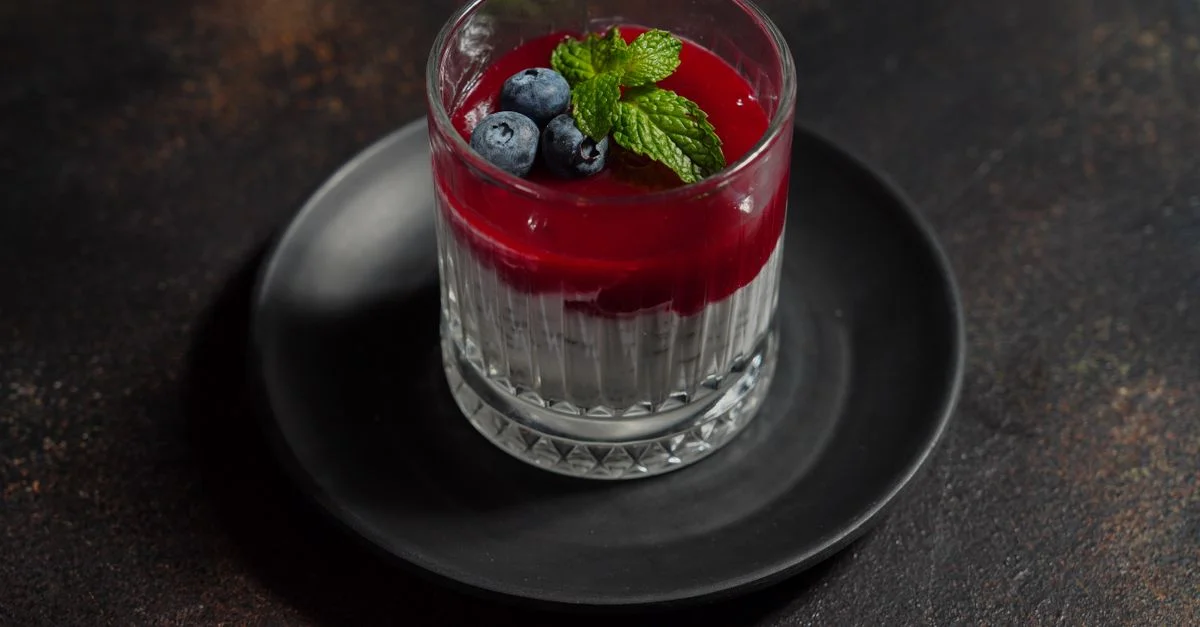 Verre à dessert élégant sur assiette avec un supplément de myrtille et de menthe. Parfait pour les présentations de gastronomie.