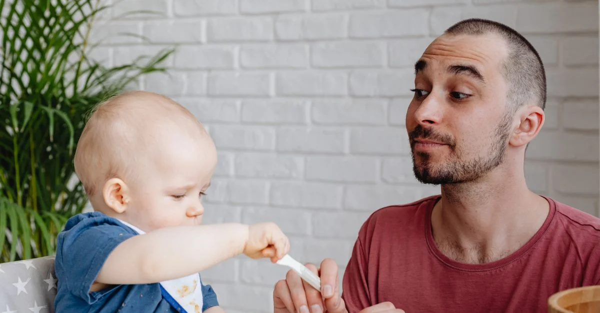 Père et bébé profitant d'un moment ludique pendant le repas à la maison.