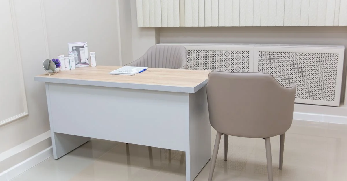 Cabinet médical minimaliste avec un bureau et des chaises modernes, parfait pour les environnements de santé.
