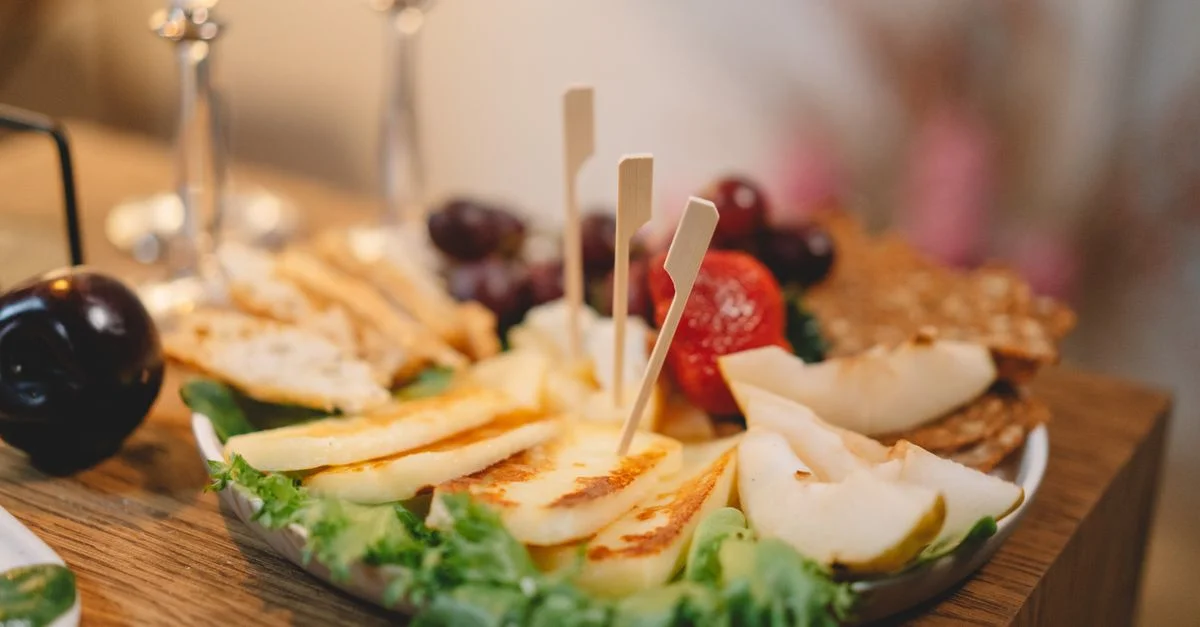 Élégant plateau de fromages et fruits avec des raisins, des poires et des tartines sur une surface en bois, parfait pour les fêtes.