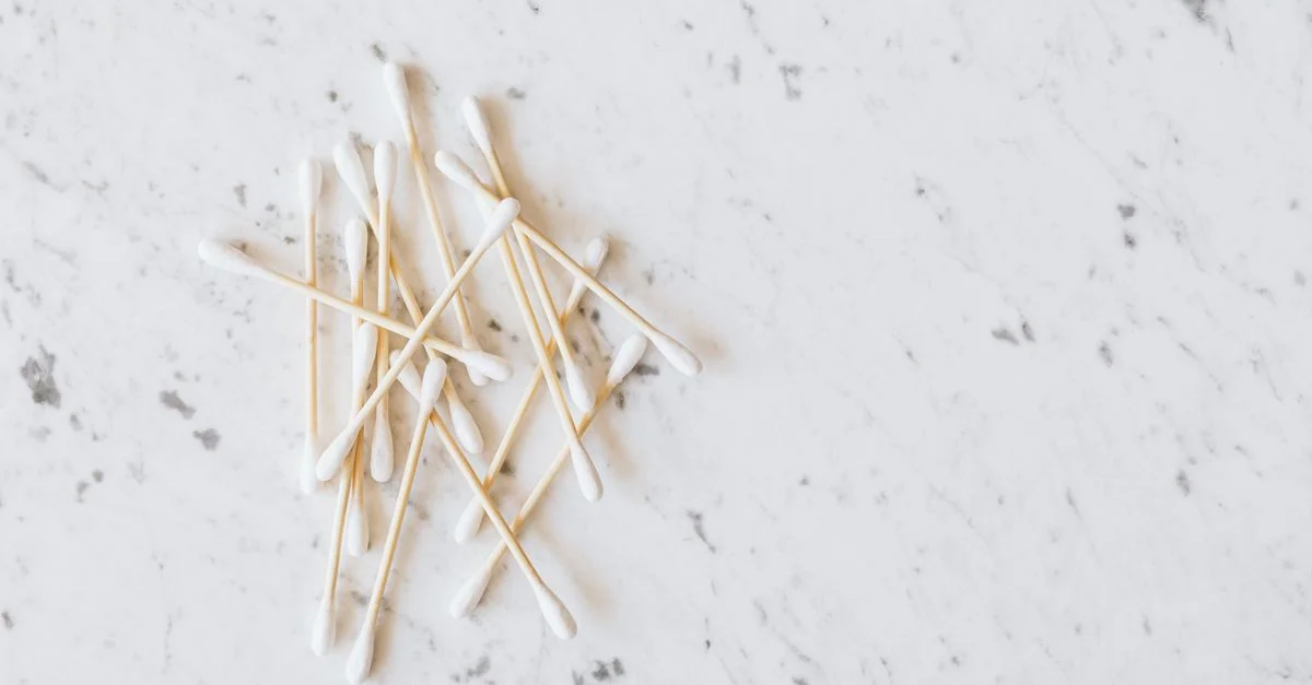 Une vue de dessus minimaliste de coton-tiges disposés sur une surface en marbre, parfait pour des thèmes d'hygiène.