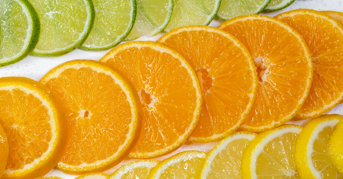 Tranches d'agrumes colorées comprenant du citron vert, de l'orange et du citron, mettant en avant la fraîcheur et la santé.