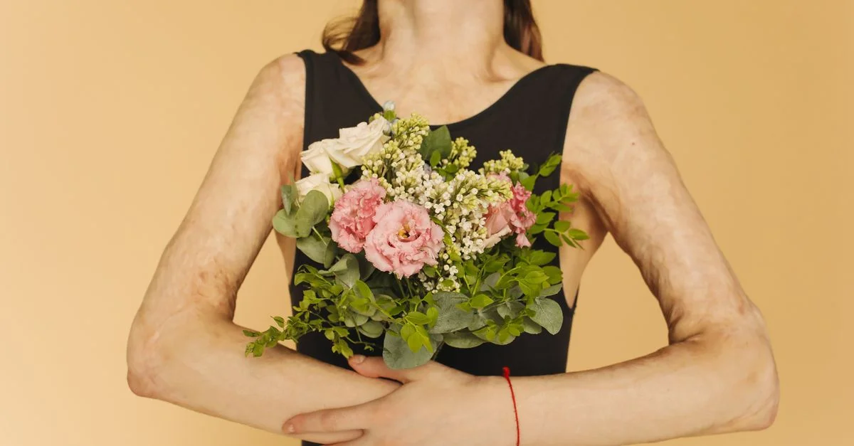 Une femme tenant un bouquet floral sur un fond beige, célébrant la beauté naturelle.