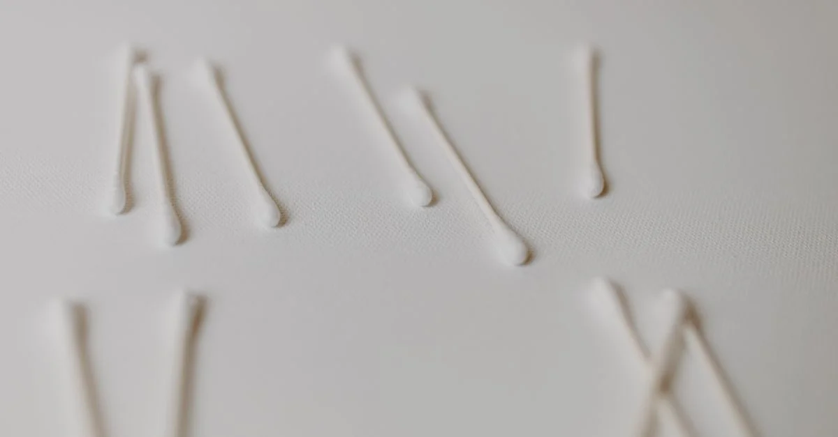 Gros plan de coton-tiges disposés sur une surface blanche, mettant en avant l'hygiène et la propreté.