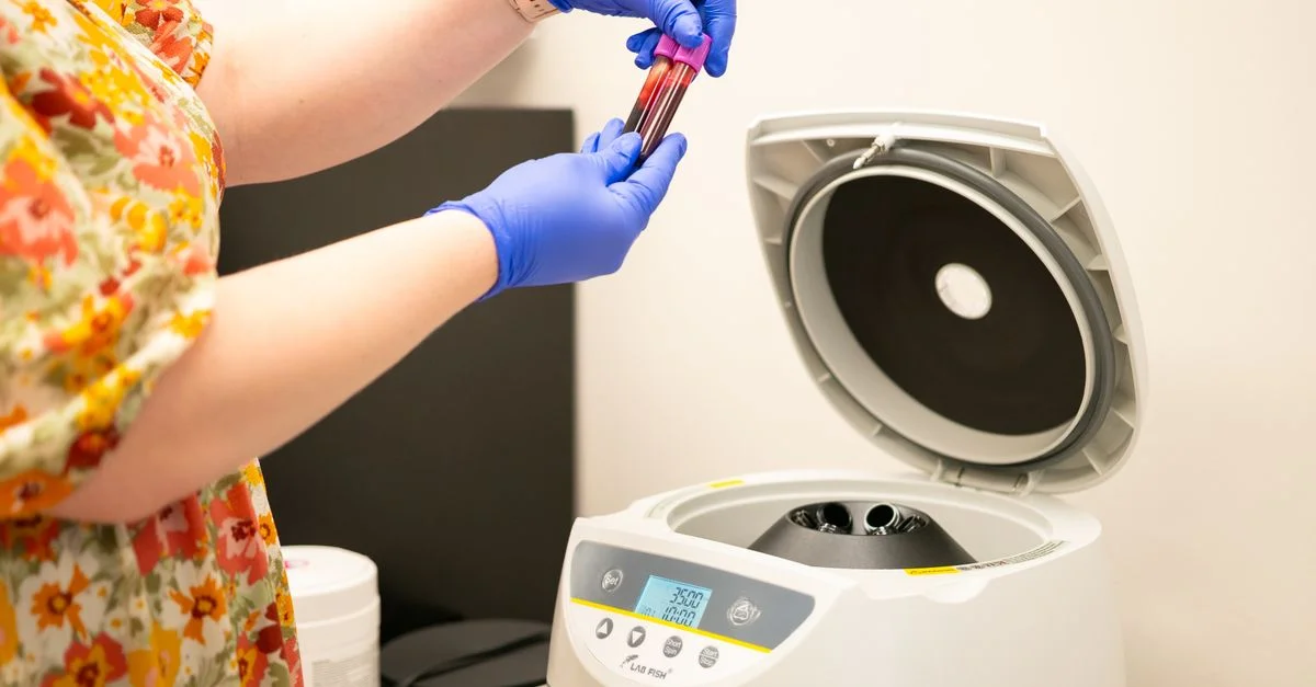 Technicien de laboratoire plaçant des échantillons de sang dans une centrifugeuse pour analyse.