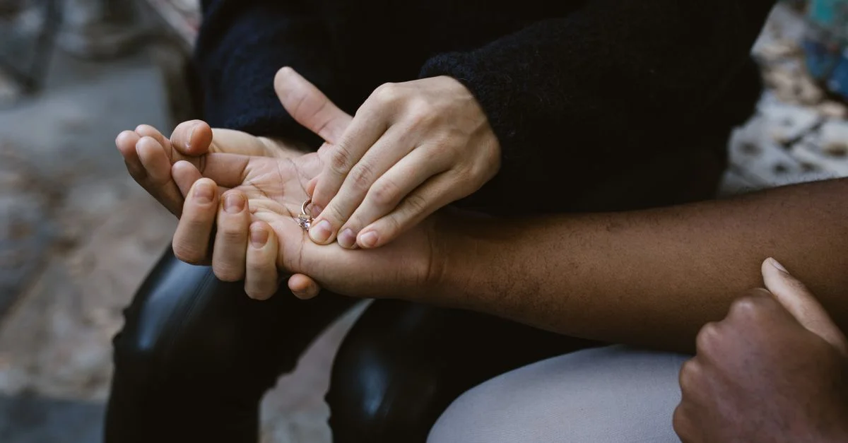 Gros plan de mains tenant une bague, symbolisant l'amour et la connexion.