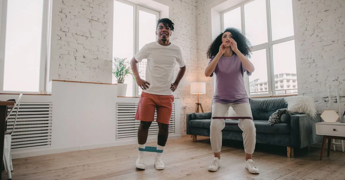 Un couple s'exerçant ensemble à la maison avec des bandes de résistance, profitant de la remise en forme en intérieur.