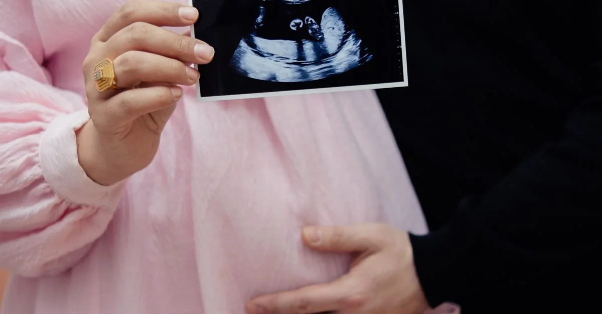 Couple enceinte tenant une image d'échographie, célébrant la nouvelle vie et le chemin de la grossesse.