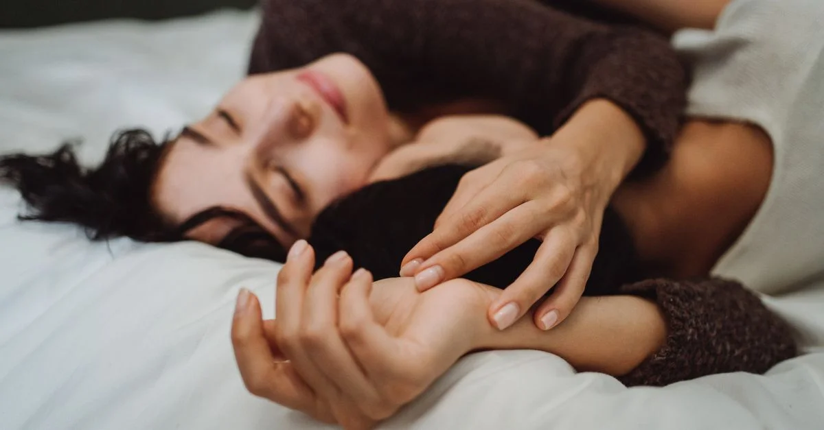 Gros plan d'un couple s'enlaçant sur un lit, véhiculant chaleur et intimité dans un cadre paisible.