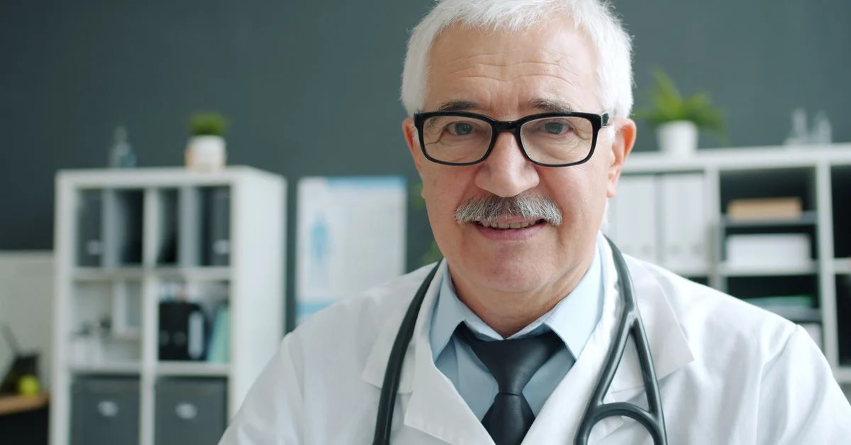 Un médecin senior, dans son bureau, portant un stéthoscope, prêt à examiner les patients.
