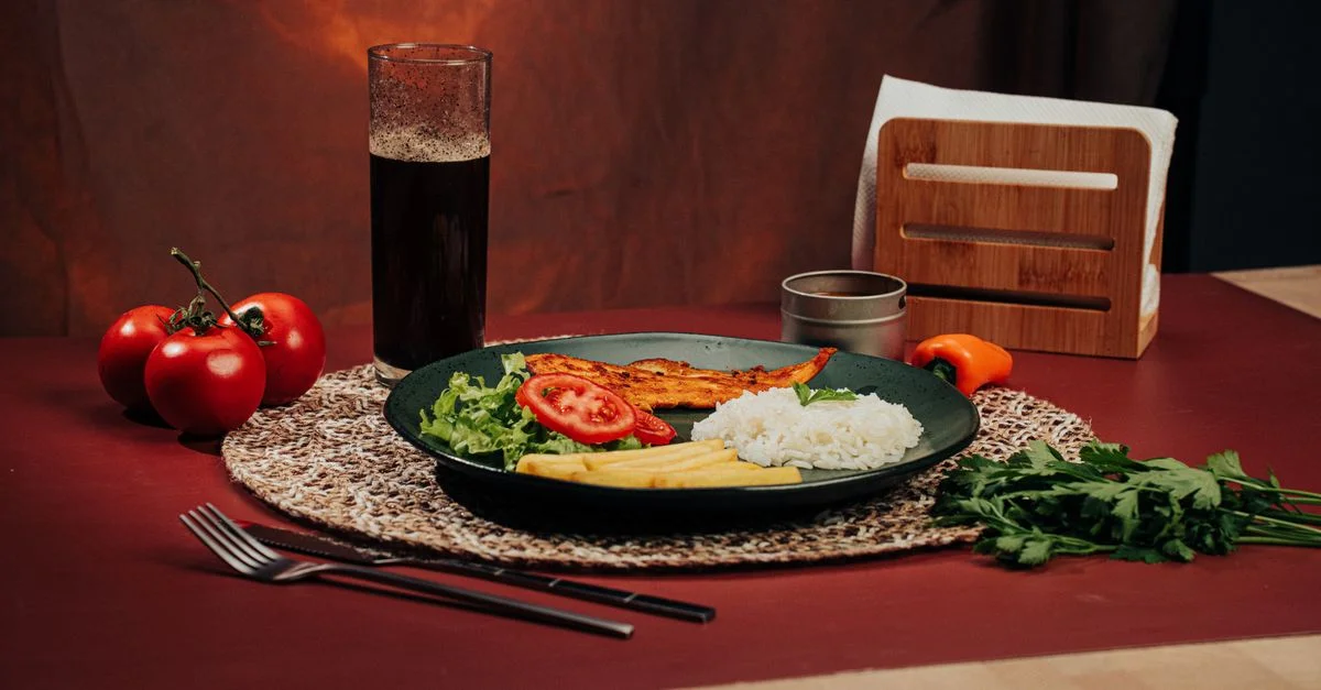 Une assiette magnifiquement dressée de riz, poulet grillé et légumes sur une table à manger.