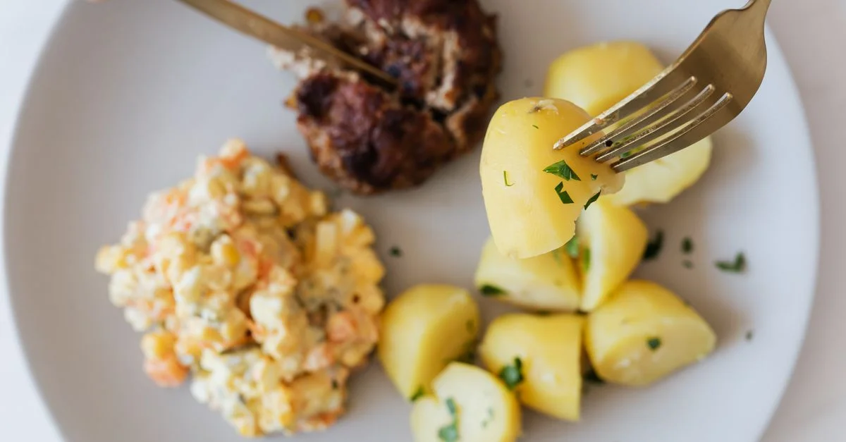 Plat savoureux de viande, pommes de terre et salade servi dans une assiette, parfait pour le déjeuner ou le dîner.