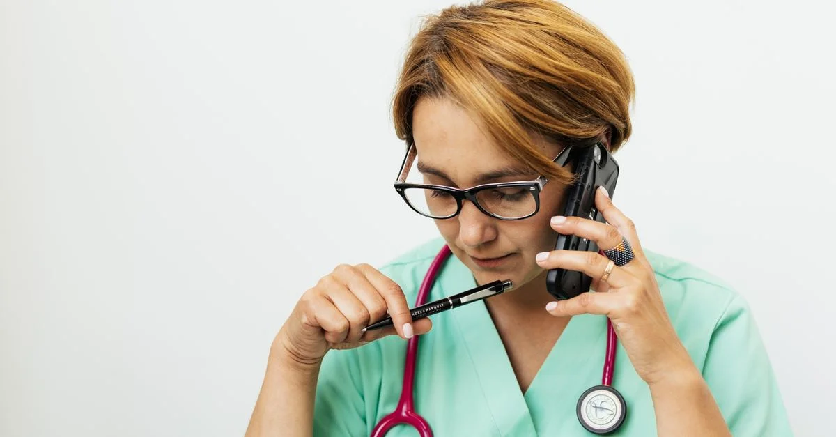 Médecin femme concentrée avec lunettes et stéthoscope parlant par téléphone pour une consultation médicale.