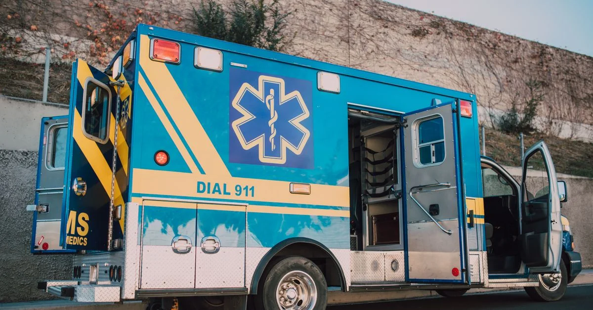 Ambulance bleue garée sur le bord de la route avec les portes ouvertes, véhicule de service médical d'urgence.