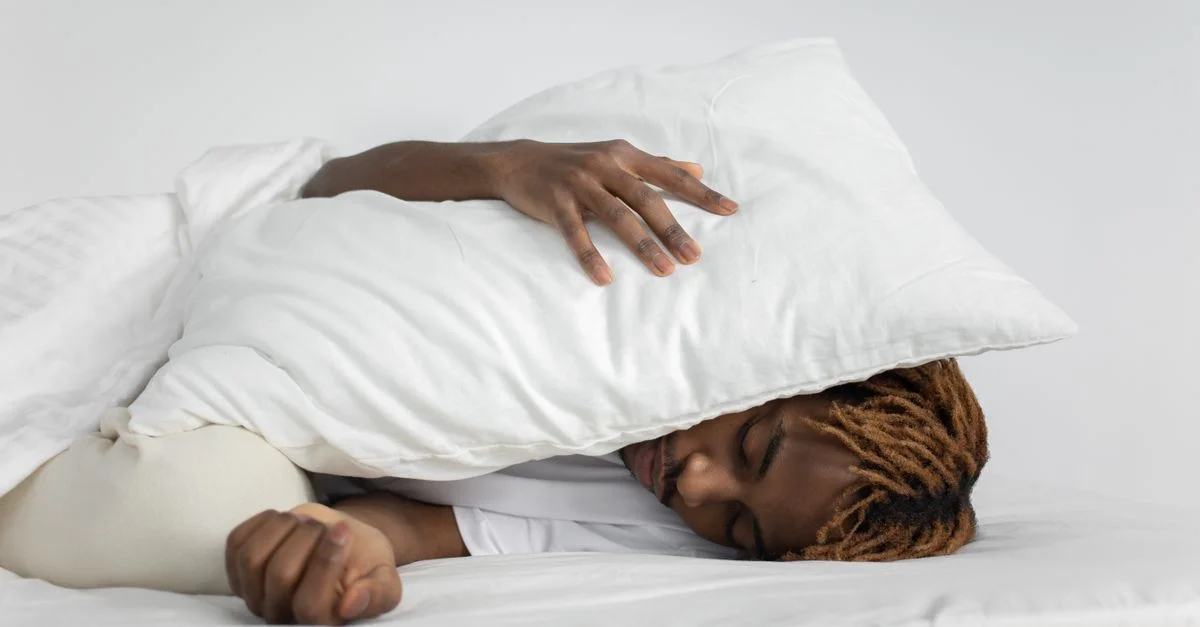 Une personne dormant paisiblement avec un oreiller couvrant son visage, mettant en avant la relaxation et le repos.