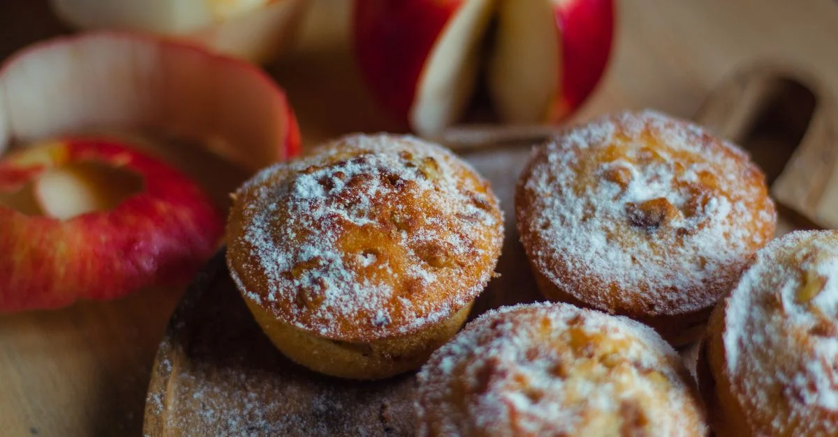 De savoureux muffins aux pommes faits maison, saupoudrés de sucre, parfaits pour un dessert douillet.