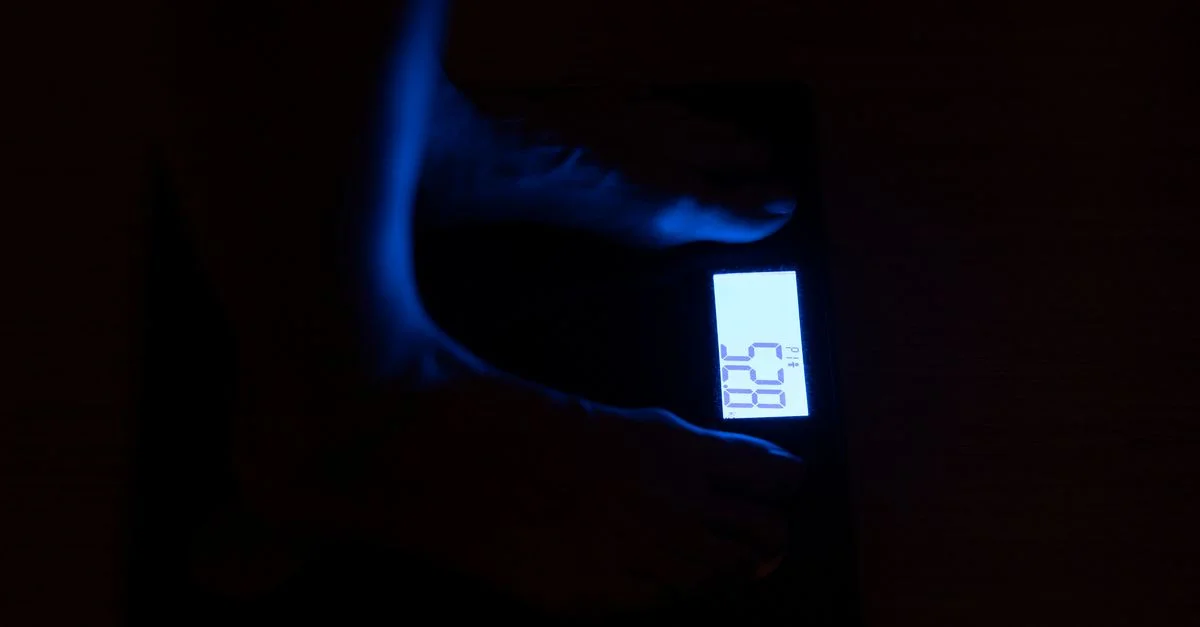 Gros plan sur une balance numérique affichant le poids dans une pièce sombre avec une illumination bleue.