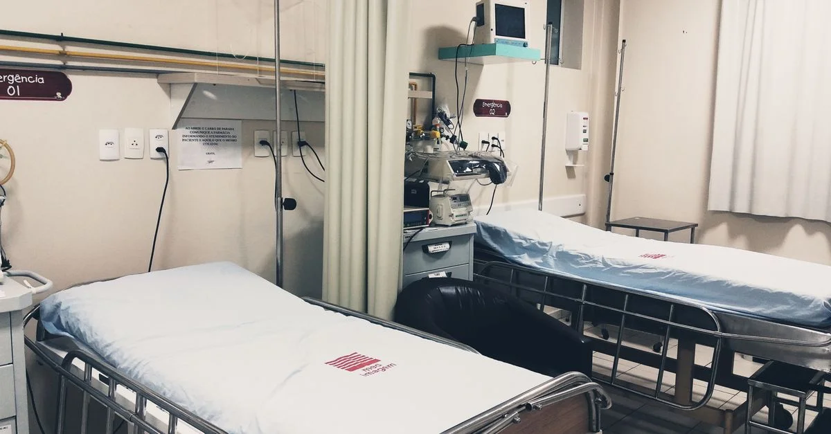 Une chambre d'hôpital vide équipée de deux lits, de matériel de surveillance et d'un éclairage d'ambiance.