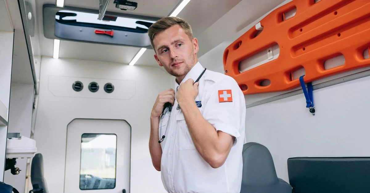 Paramédic se tenant à l'intérieur de l'ambulance, tenant un stéthoscope, prêt pour l'intervention d'urgence.