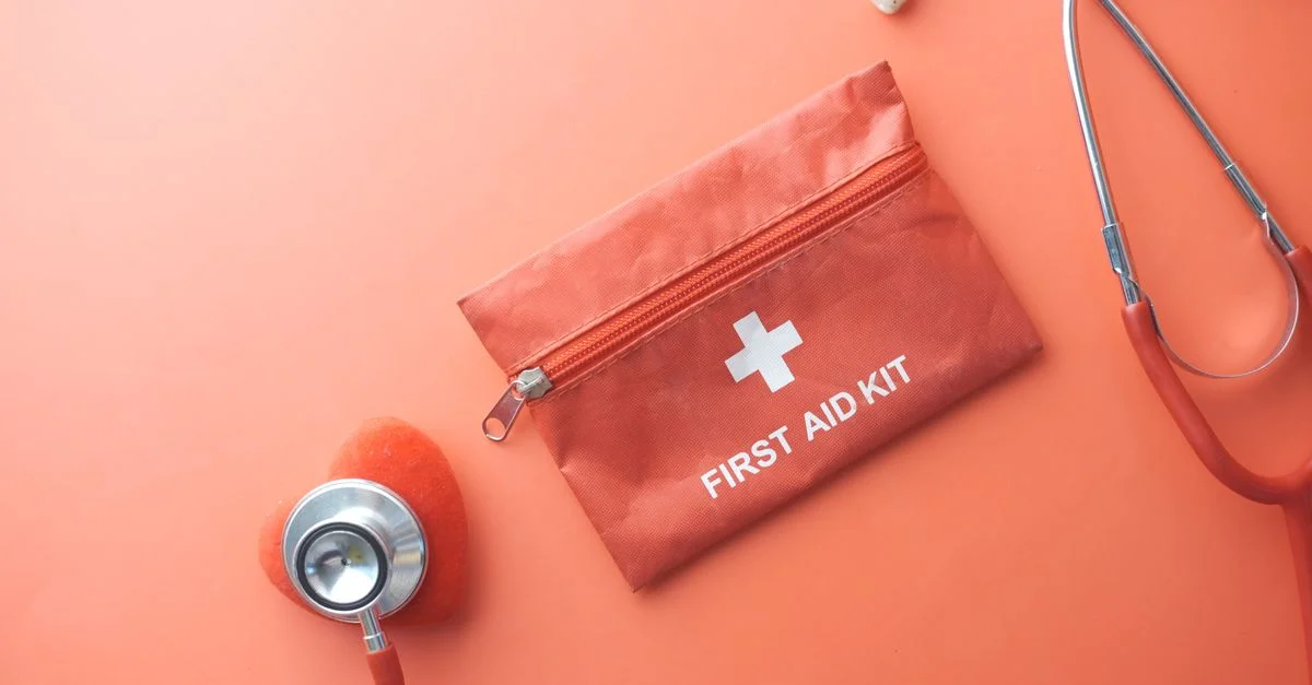 Outils médicaux comprenant un stéthoscope et une trousse de premiers secours sur une surface rose, parfaits pour des thèmes de santé.