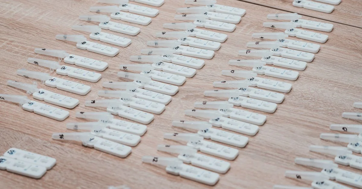 Plusieurs kits de test COVID-19 soigneusement disposés sur une table en bois à l'intérieur.
