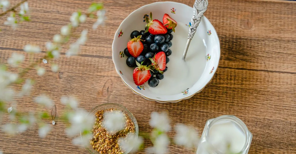 Un bol de fraises fraîches, de myrtilles avec du yaourt sur une table en bois, vu d'en haut.