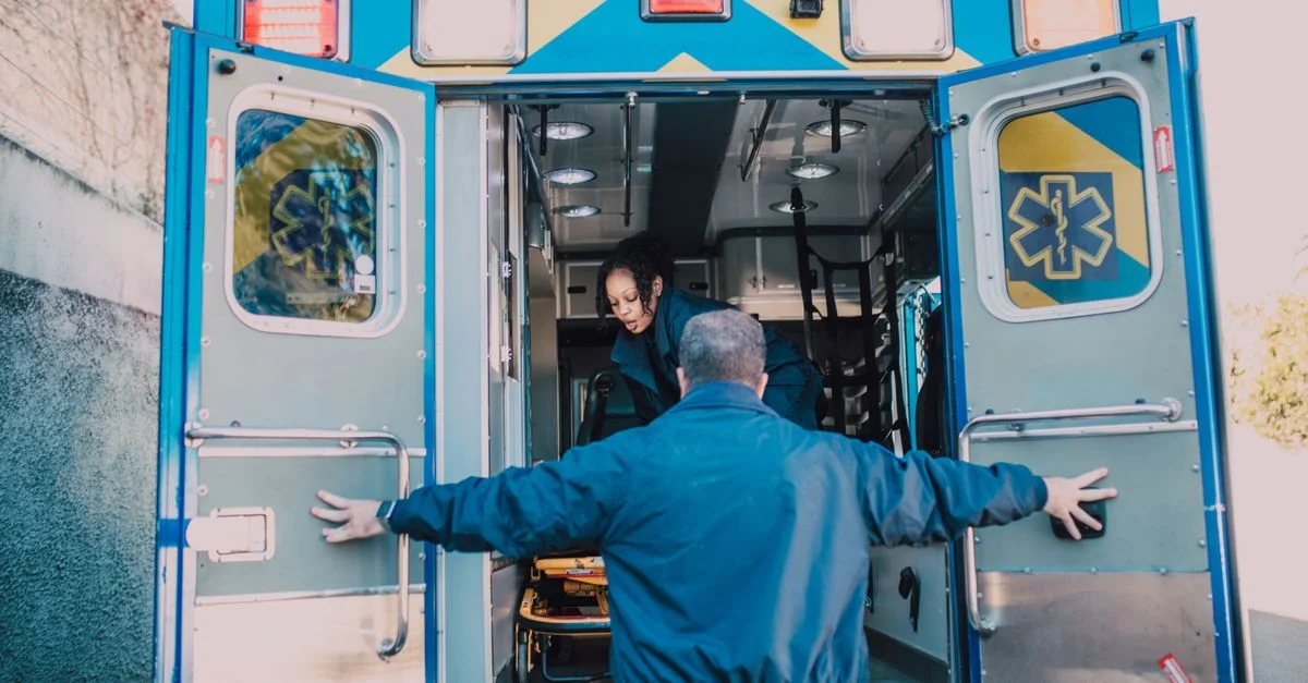 Des paramédics chargent du matériel dans une ambulance, se préparant pour un appel d'urgence.