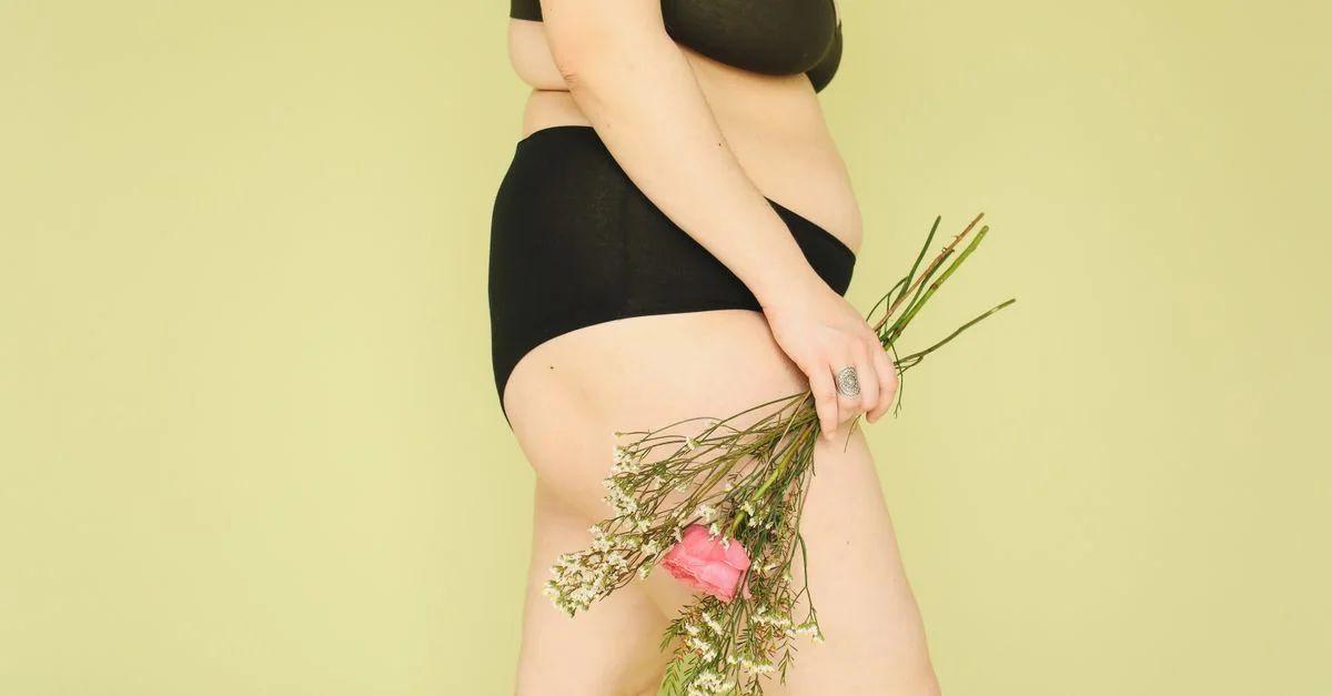 Une femme confiante en lingerie tenant des fleurs, célébrant la positivité corporelle.