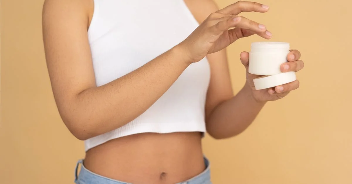 Gros plan sur une jeune femme appliquant de la crème pour le visage, mettant en avant une peau saine et un mode de vie.