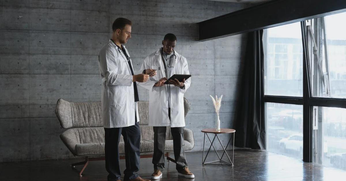 Deux médecins dans un bureau industriel discutent des données des patients sur une tablette numérique.