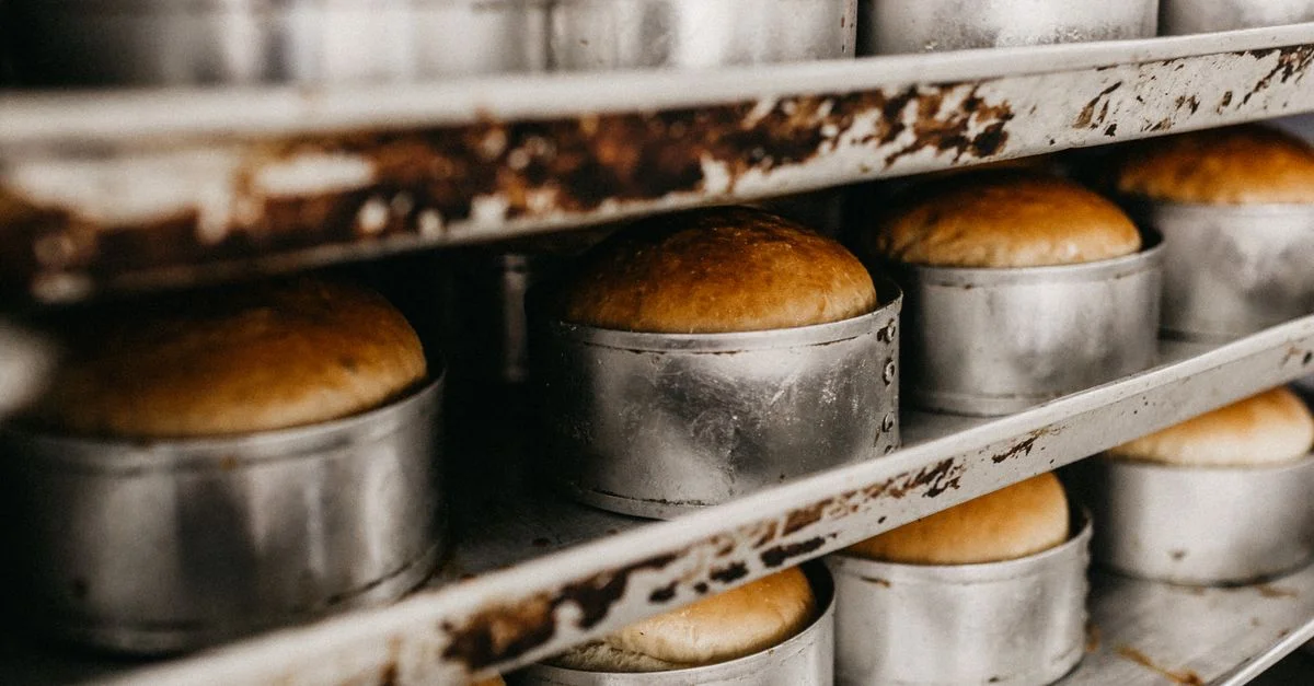 Gros plan de pain fraîchement cuit dans un plat en métal sur une étagère de boulangerie.