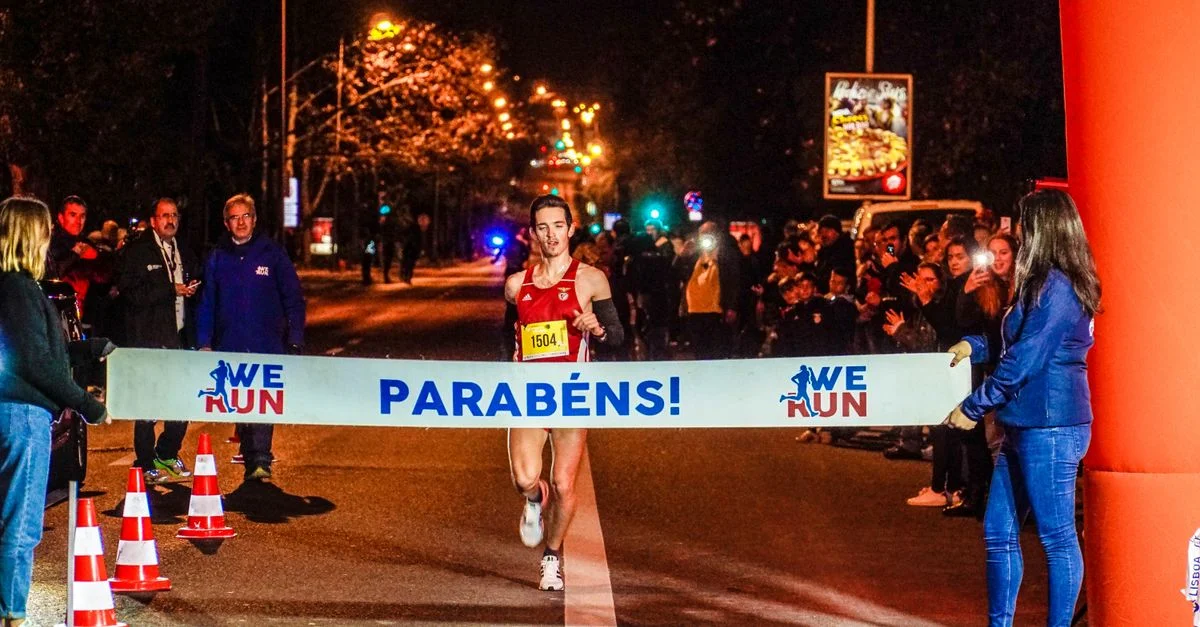 Un coureur franchit la ligne d'arrivée lors d'un marathon nocturne, célébrant sa victoire.