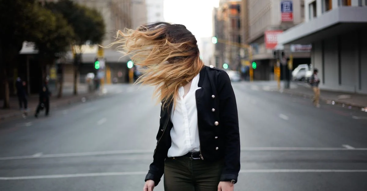 Femme élégante dans un Johannesburg urbain avec des cheveux en mouvement. Scène de rue à la mode.