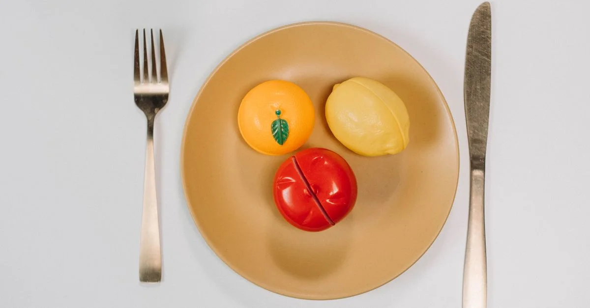 Fruits en jouet colorés sur une assiette avec des couverts dans une disposition conceptuelle en plongée.