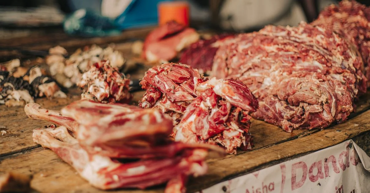 Gros plan sur des découpes de viande fraîches exposées sur une table en bois de marché, parfaites pour des visuels culinaires.