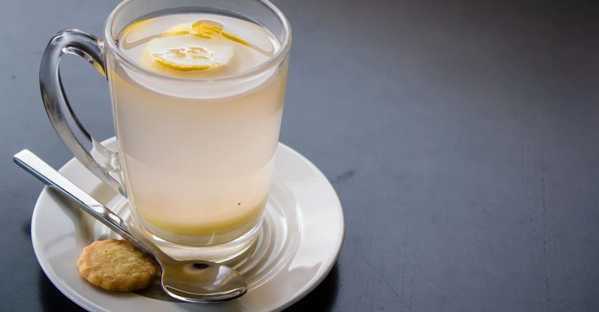 Eau infusée au citron rafraîchissante dans un verre transparent avec biscuit et sous-tasse, parfait pour un mode de vie axé sur la santé.