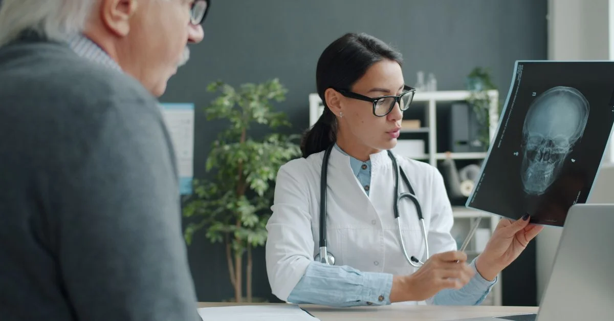 Une femme médecin discute d'une radiographie cérébrale avec une patiente âgée dans un cabinet médical moderne.