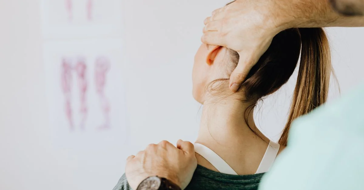 Un chiropracteur effectuant un ajustement thérapeutique du cou sur une patiente dans un cadre clinique.