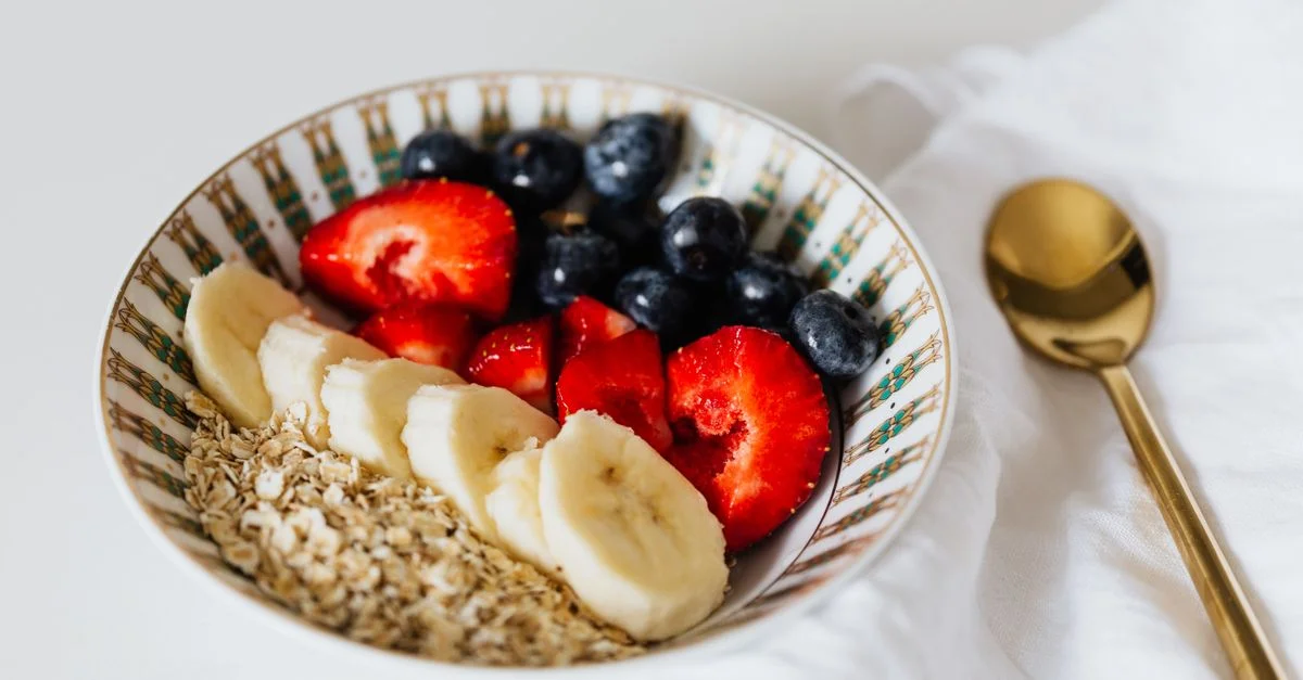 Un bol vibrant de flocons d'avoine avec des bananes tranchées, des fraises et des bleuets, idéal pour un petit-déjeuner sain.