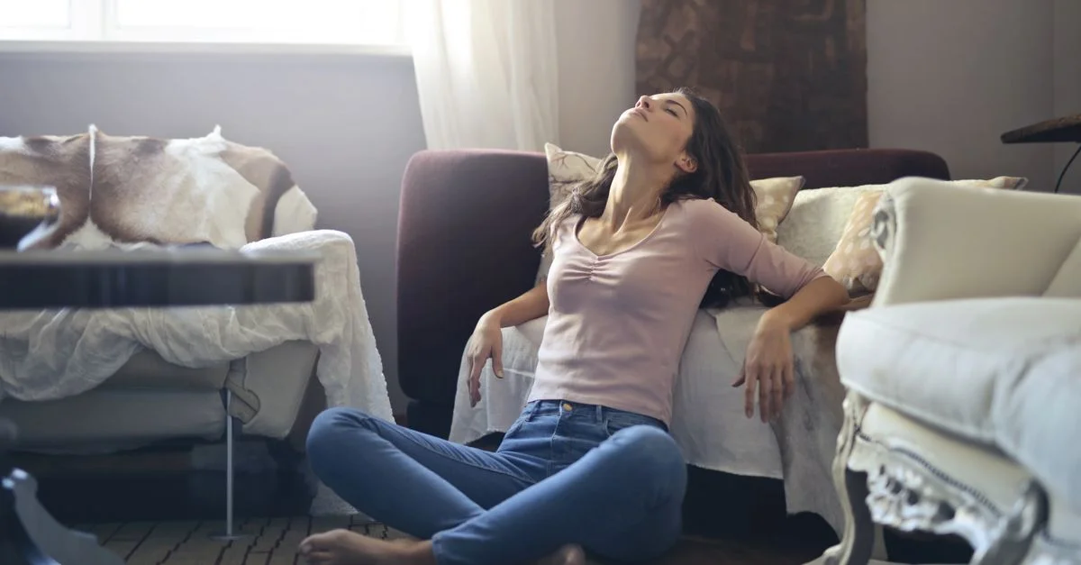 Femme assise par terre dans une pose détendue, profitant d'un moment paisible dans un salon cosy.