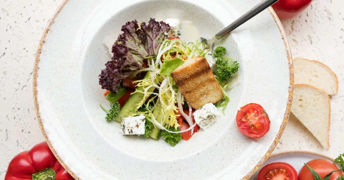 Salade de légumes sains avec du pain grillé et du fromage sur une assiette en céramique.