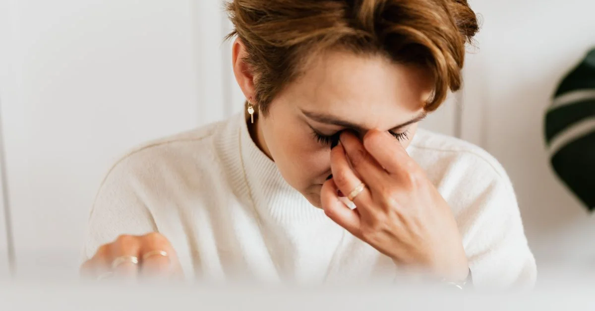 Un gros plan d'une femme se frottant les yeux, exprimant le stress et la fatigue à l'intérieur.