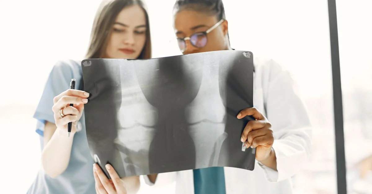 Deux médecins femmes analysant une image radiographique dans une clinique lumineuse.
