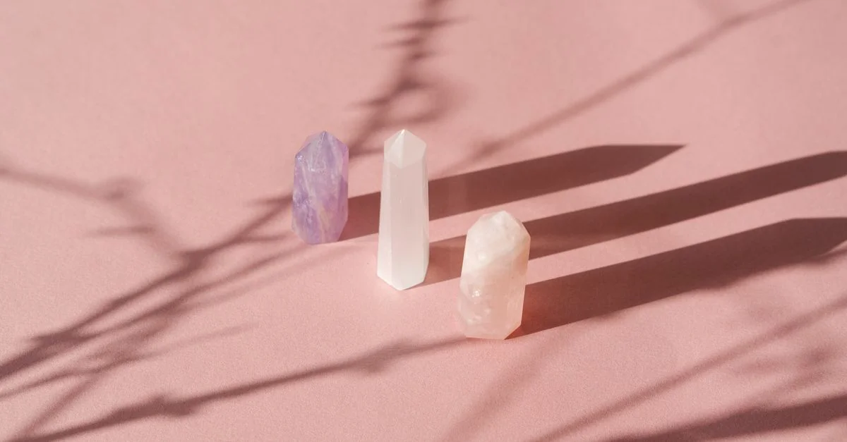 Une composition artistique de cristaux projetant des ombres sur un fond rose doux, créant une composition de nature morte sereine.