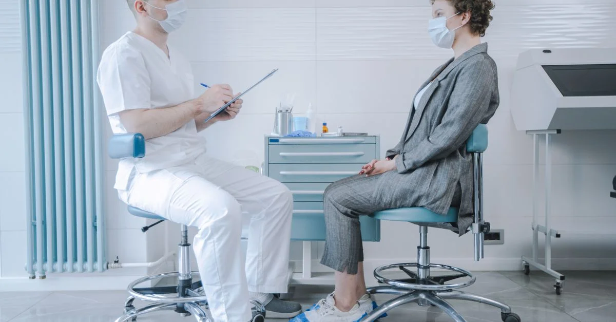 Médecin et patient portant des masques lors d'une consultation en milieu clinique.