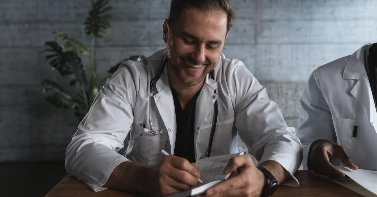 Un médecin souriant prenant des notes dans un cadre médical.
