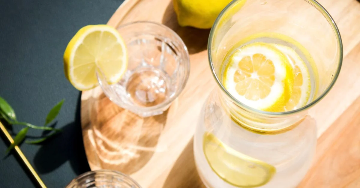 Vue de dessus de l'eau infusée au citron et du verre sur un plateau en bois, idéal pour les thèmes de mode de vie sain.