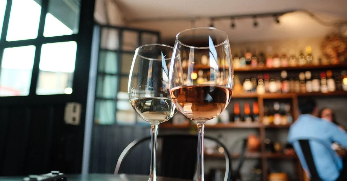 Deux verres à vin sur une table dans un bar confortable avec des bouteilles en arrière-plan, parfaits pour des thèmes sociaux ou de style de vie.