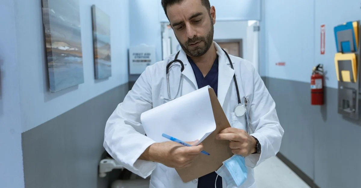 Un médecin en blouse blanche consulte un dossier médical dans un couloir d'hôpital.