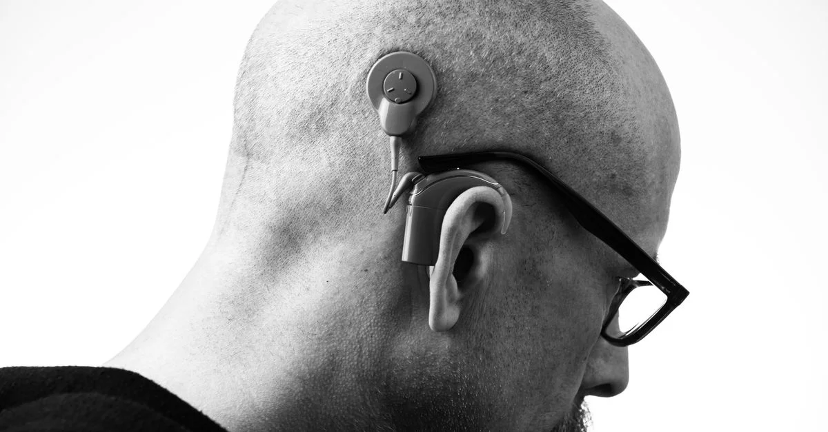 Profil noir et blanc d'un homme portant des lunettes et un appareil auditif, prise en studio.
